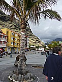 Tazacorte (puerto), Bummel durch das kleine Badeörtchen, links hinter den Appartementhäusern erheben sich die Felsen zum 'El Time' hoch, geradeaus sieht man die Öffnung des 'Barranco de las Angustias', der in die 'Caldera de Taburiente' führt